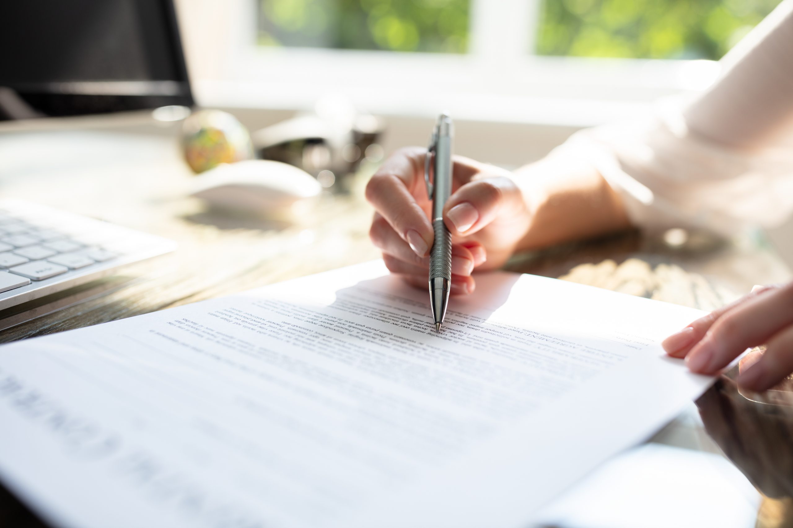 A woman signing a contract with a pen. If you have a breach of contract and require legal assistance, contact our Oakland employment law attorney.