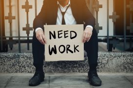 An unemployed man holding a sign saying 'need work.' If you were wrongfully terminated, call our San Francisco attorney today.