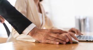 Boss with hand on top of woman controlling mouse, to show improper touching and needing to prove San Jose Sexual Harassment with an Attorney