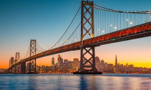 The Bay Bridge spans across the water with the San Francisco skyline in the background at sunset for Reasonable Accommodations in San Francisco consult with our lawyers.